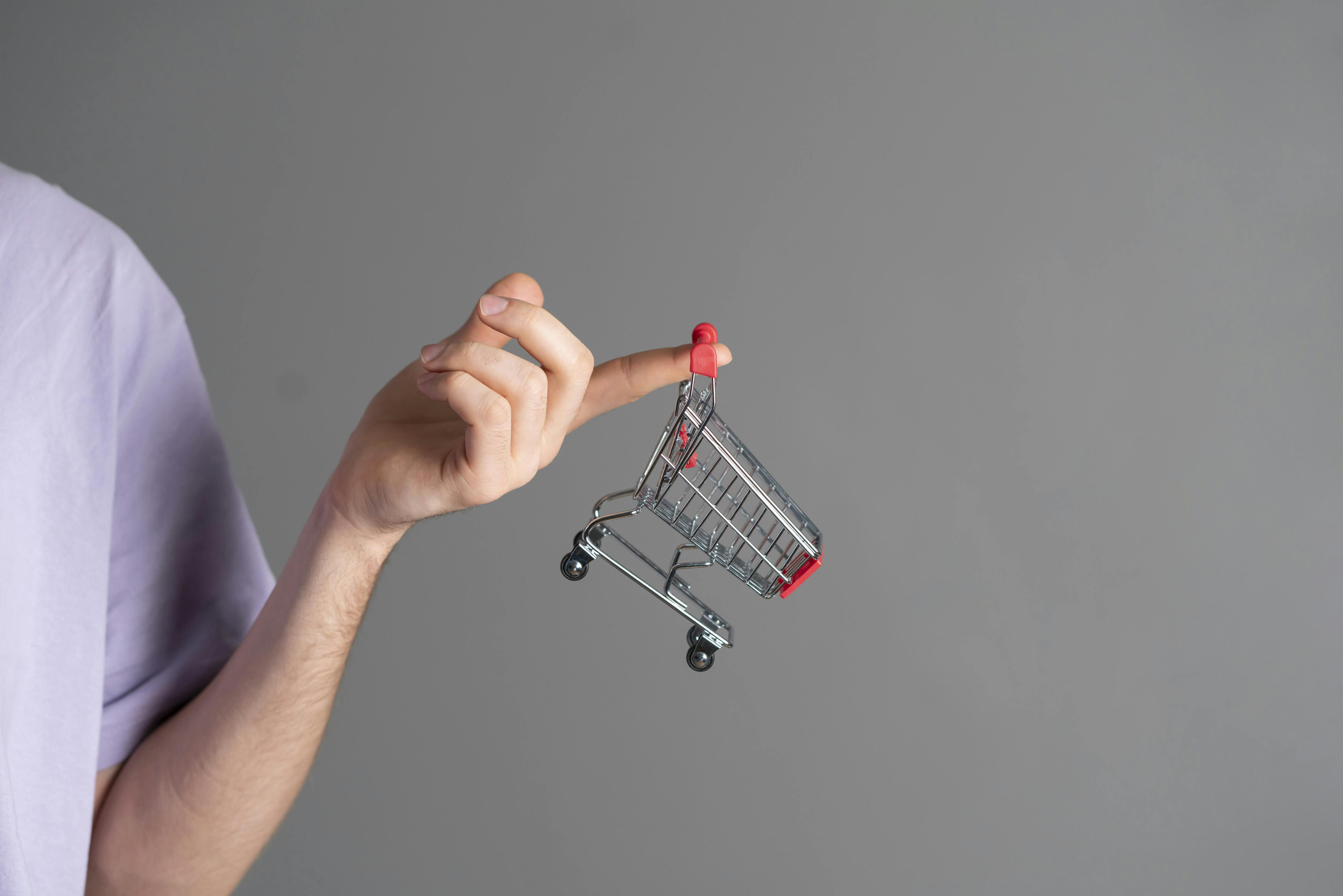  a hand holding a miniature shopping cart