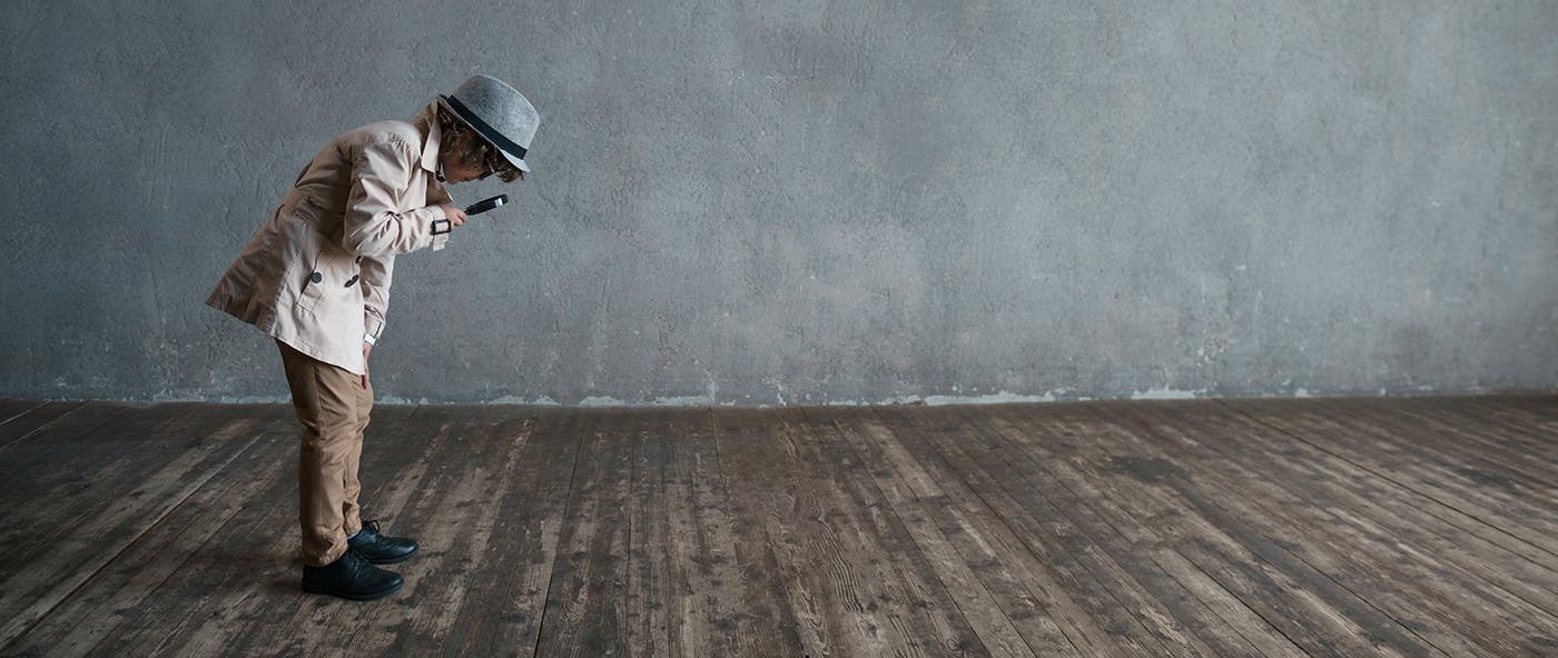 A child in a fedora with a magnifying glass