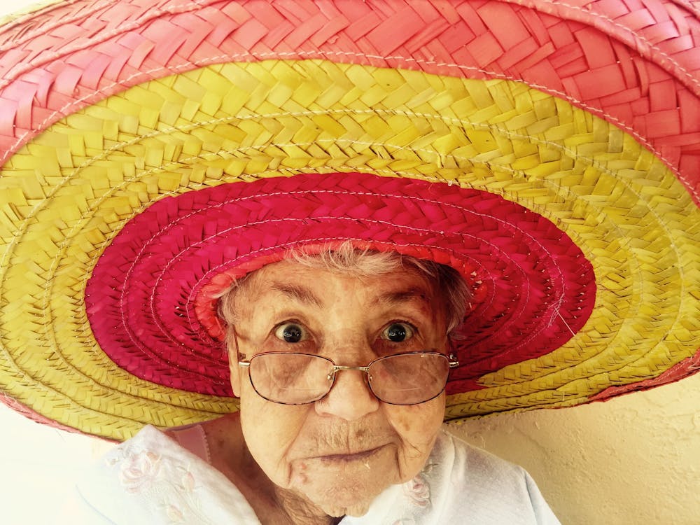 Old woman wearing brightly coloured sombrero looking at the camera Old woman wearing brightly coloured sombrero looking at the camera