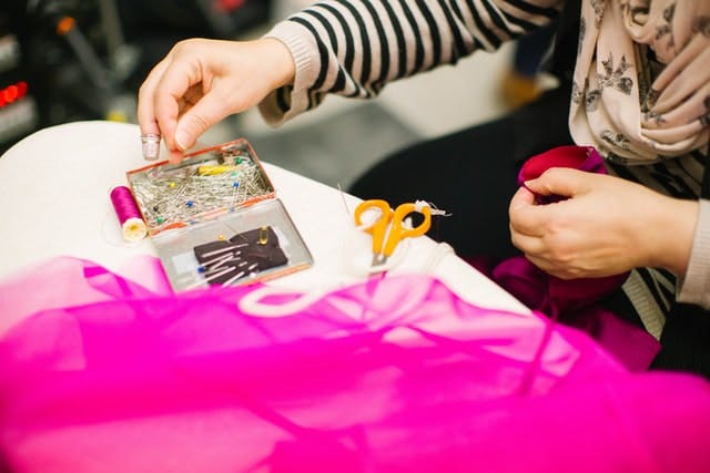  close up of someone sewing bright pink tulle