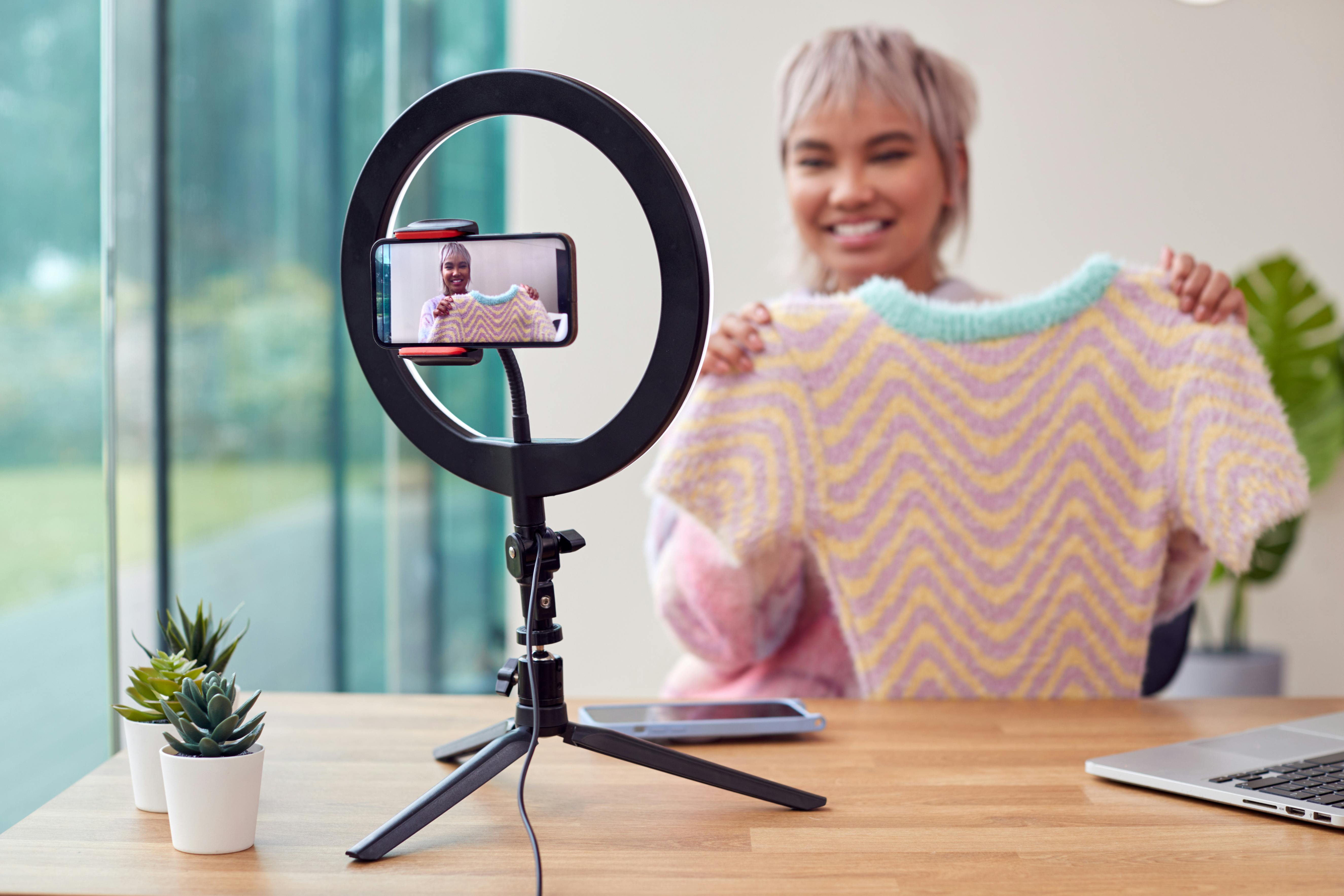  person recording themselves showing hand knitted top to camera