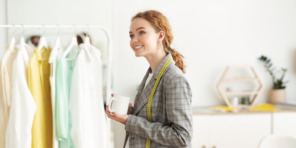 A fashion designer standing next a rack of clothing A fashion designer standing next a rack of clothing