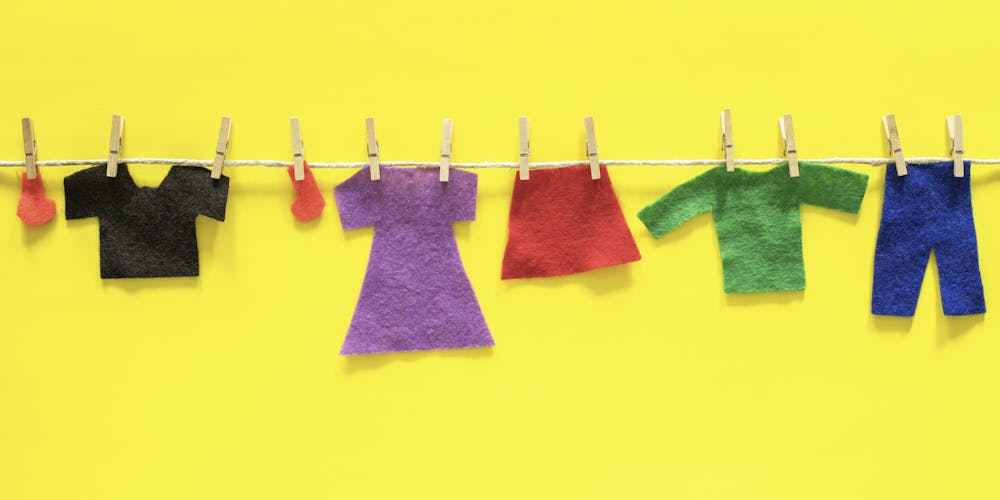 felt clothing for dolls hanging on yellow background felt clothing for dolls hanging on yellow background