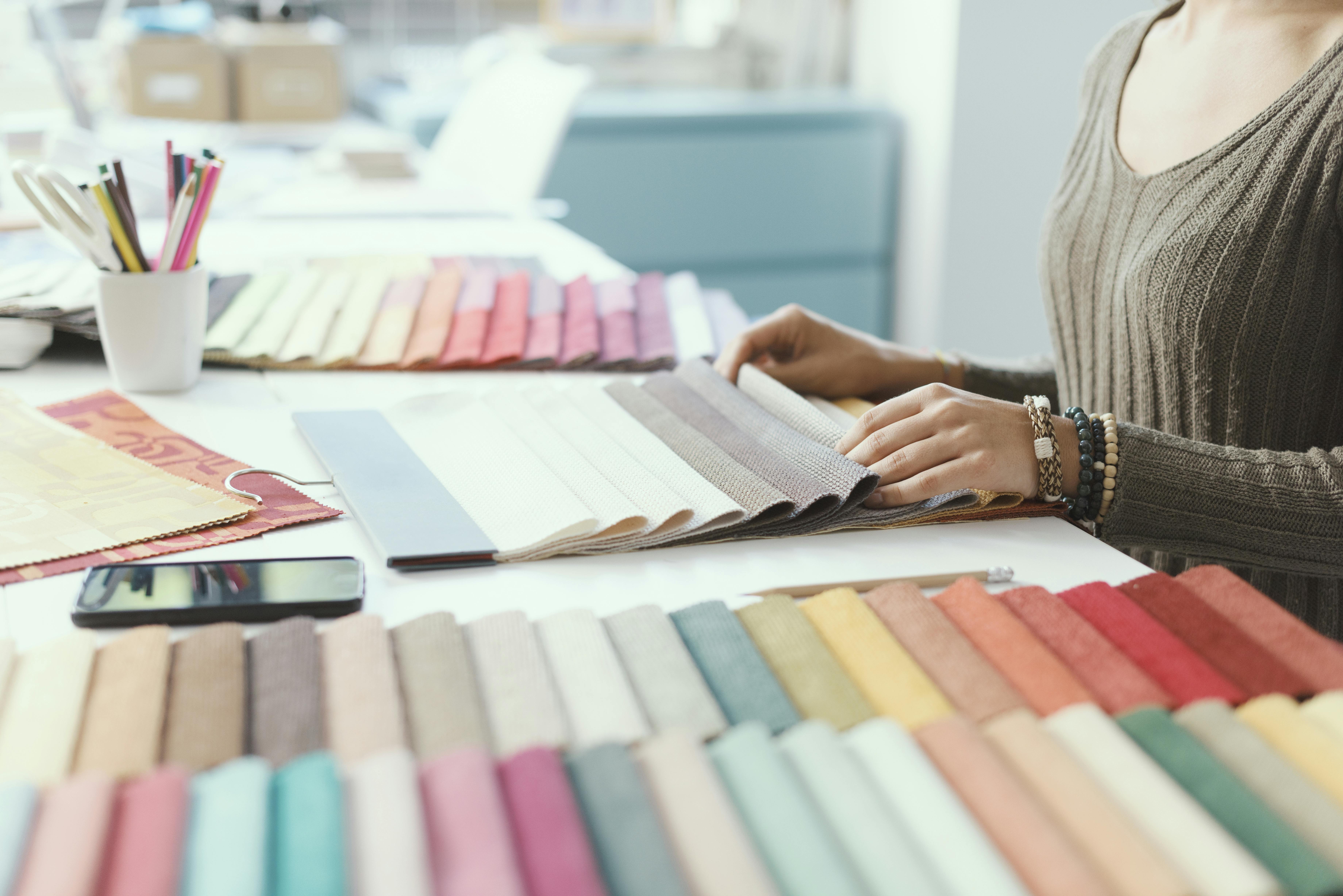  woman looking at multicolored fabric swatches at desk