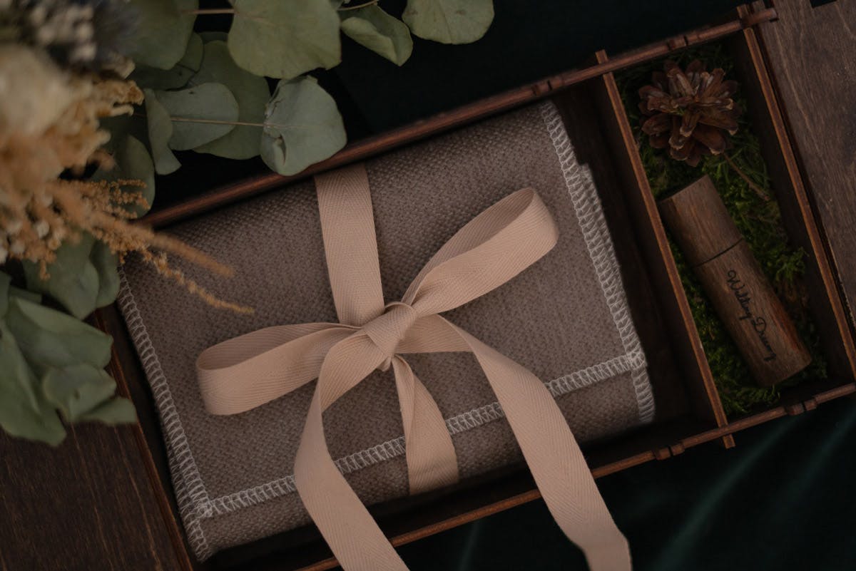 Cadeau de mariage fait à la main emballé avec un nœud rose et du feuillage en arrière-plan