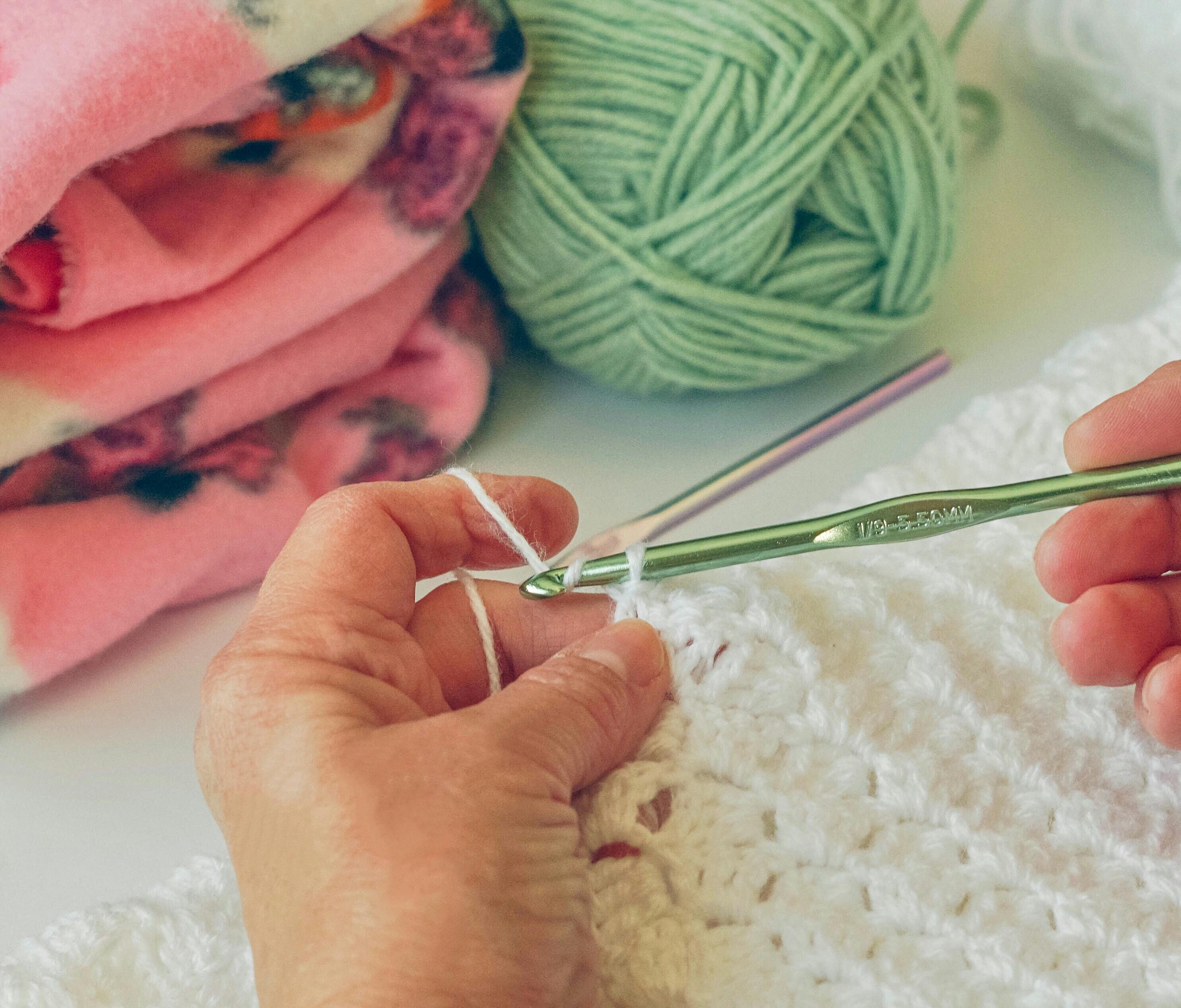  hands crocheting white blanket