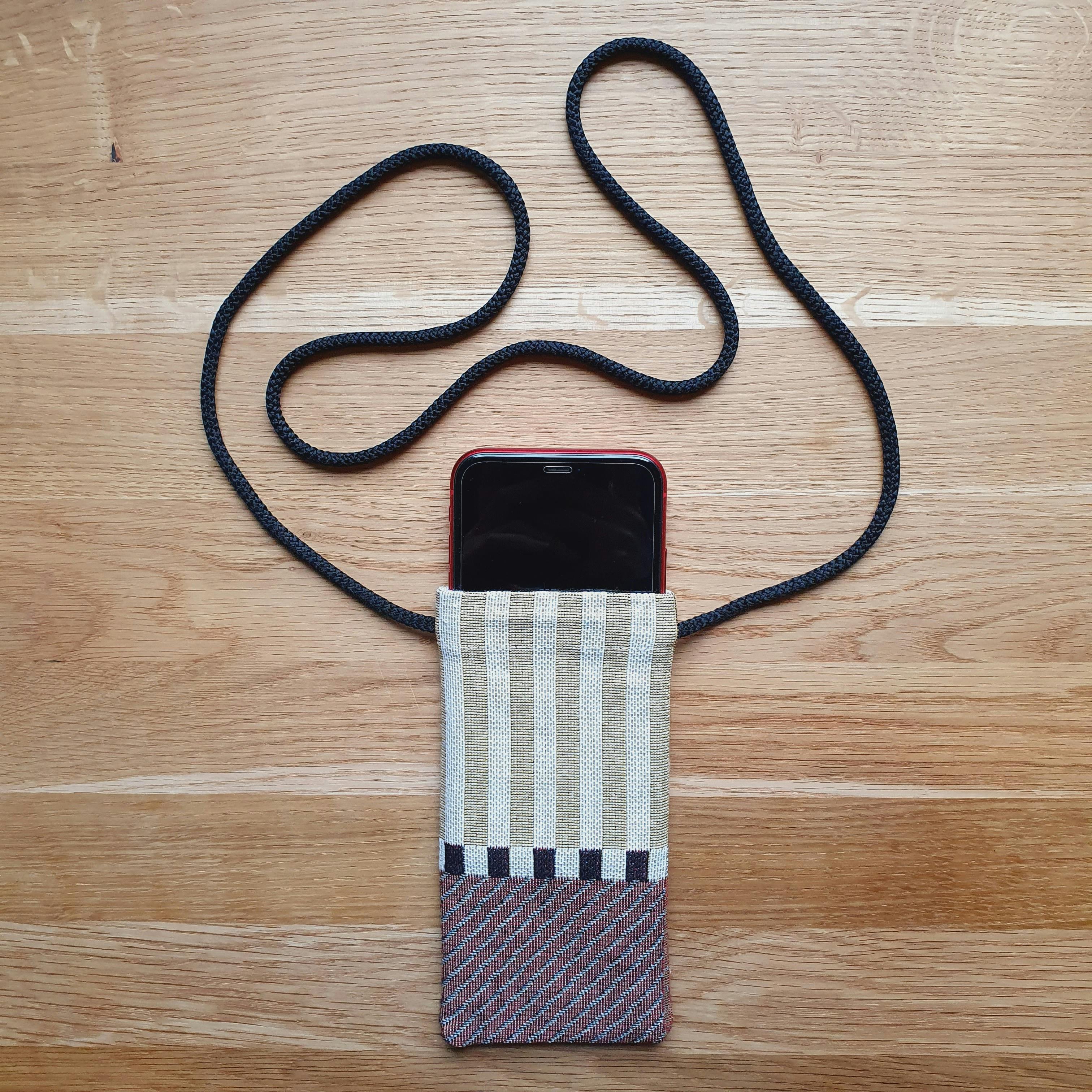  funda para iPhone hecha a mano en tela tejida a rayas con cordón para el cuello y el teléfono guardado en el interior
