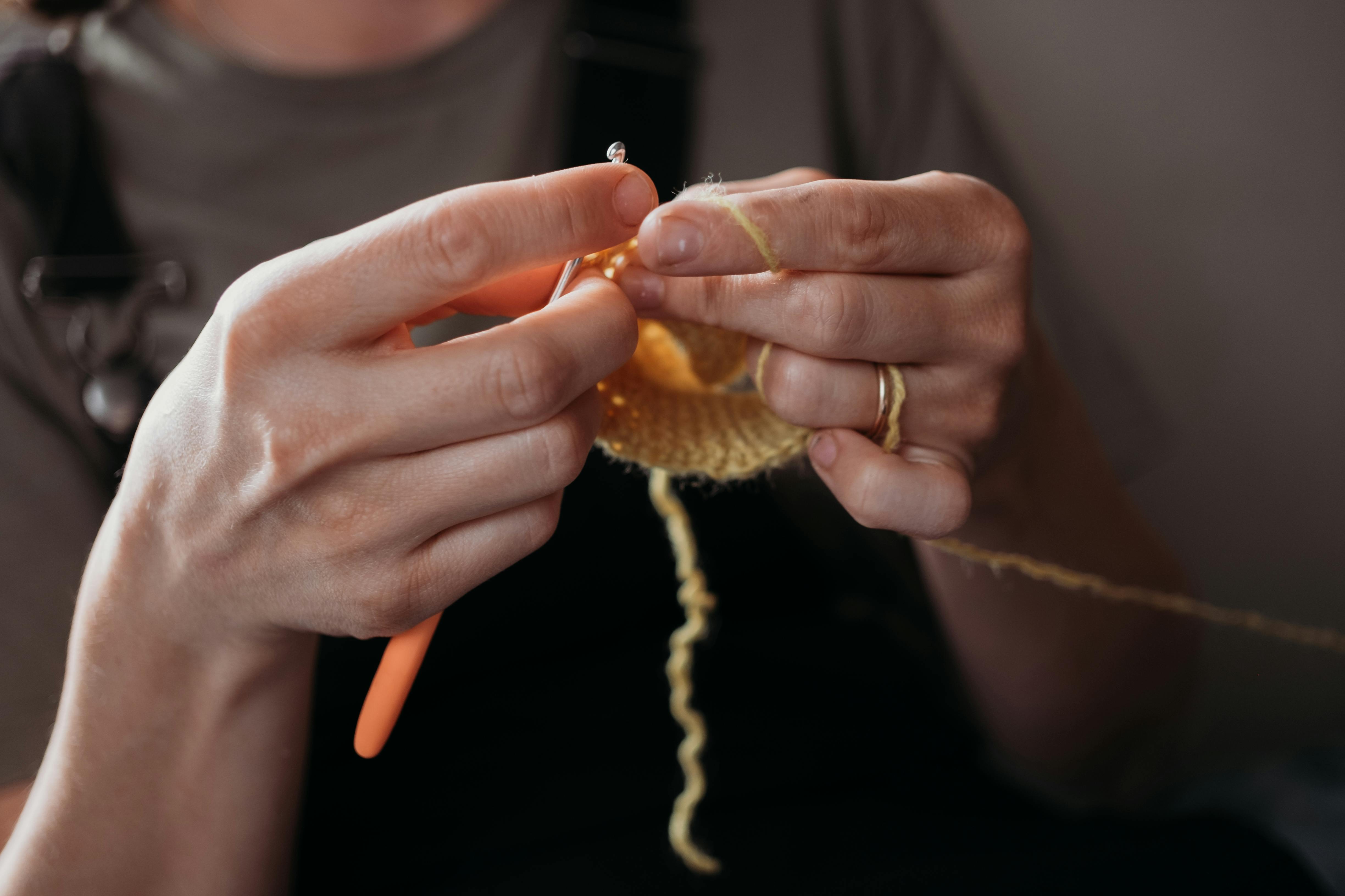  womans hands crocheting an item