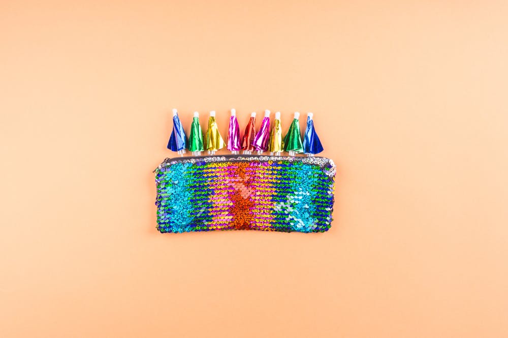 fotografia di una pochette di paillettes color arcobaleno con ombrellini da cocktail fotografia di una pochette di paillettes color arcobaleno con ombrellini da cocktail