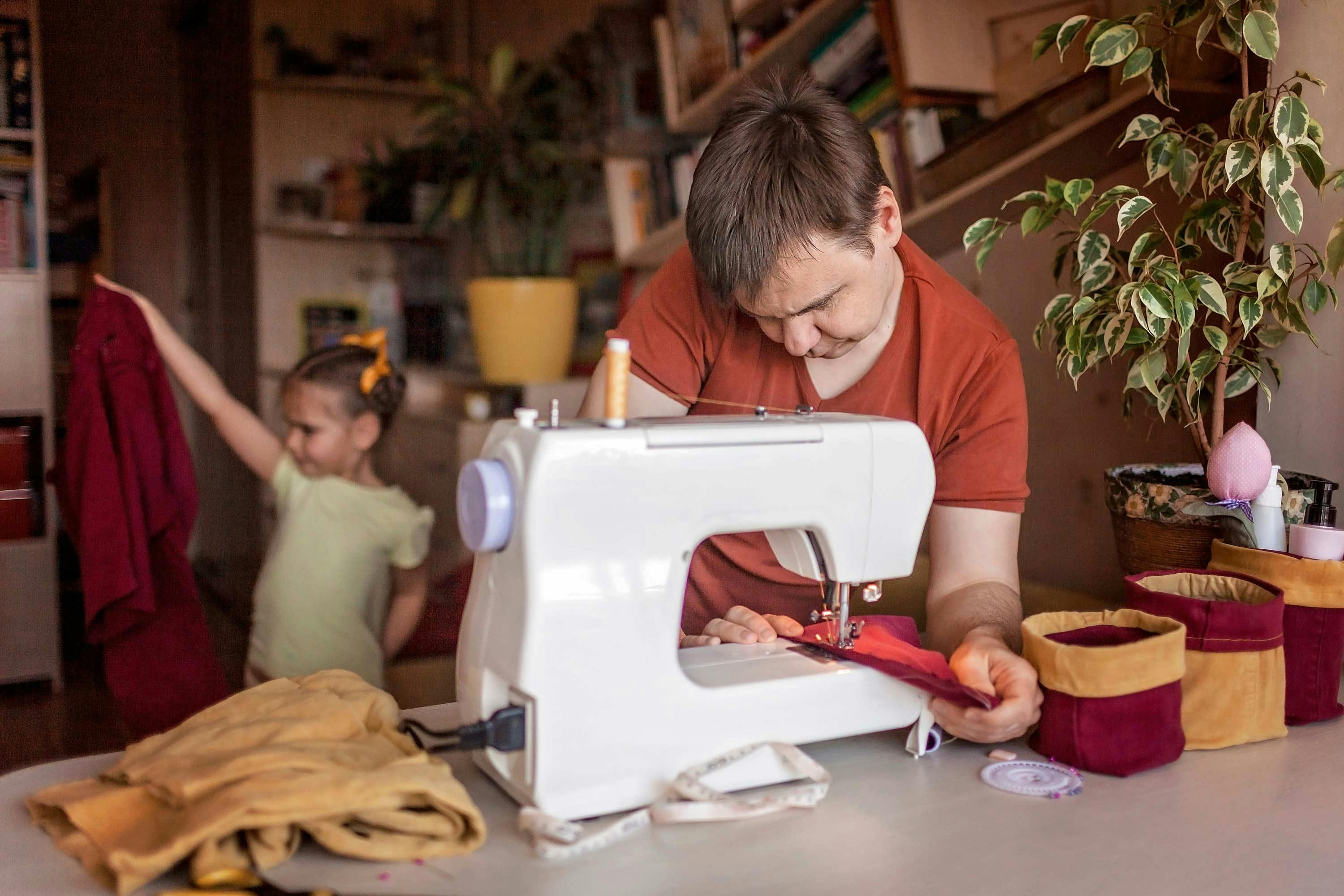  Man sewing in home studio with young child