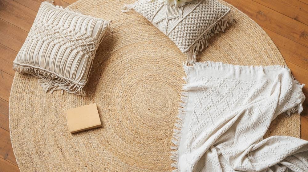  Macrame pillows on jute rug with woven blanket and book.