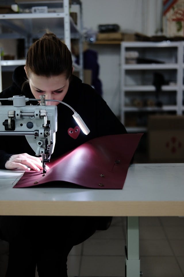  person sewing red vinyl fabric on sewing machine