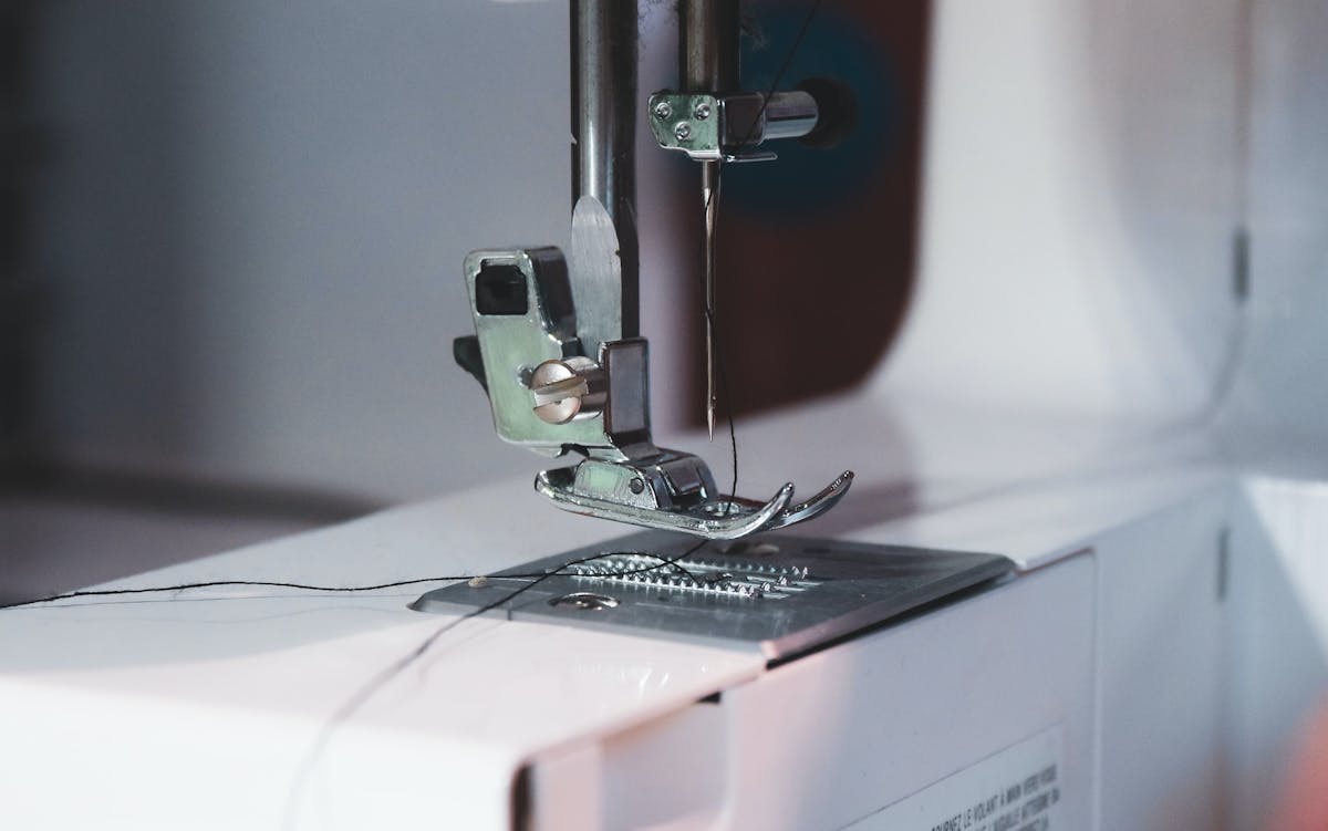  primer plano de una prensaleta de una máquina de coser con hilo negro