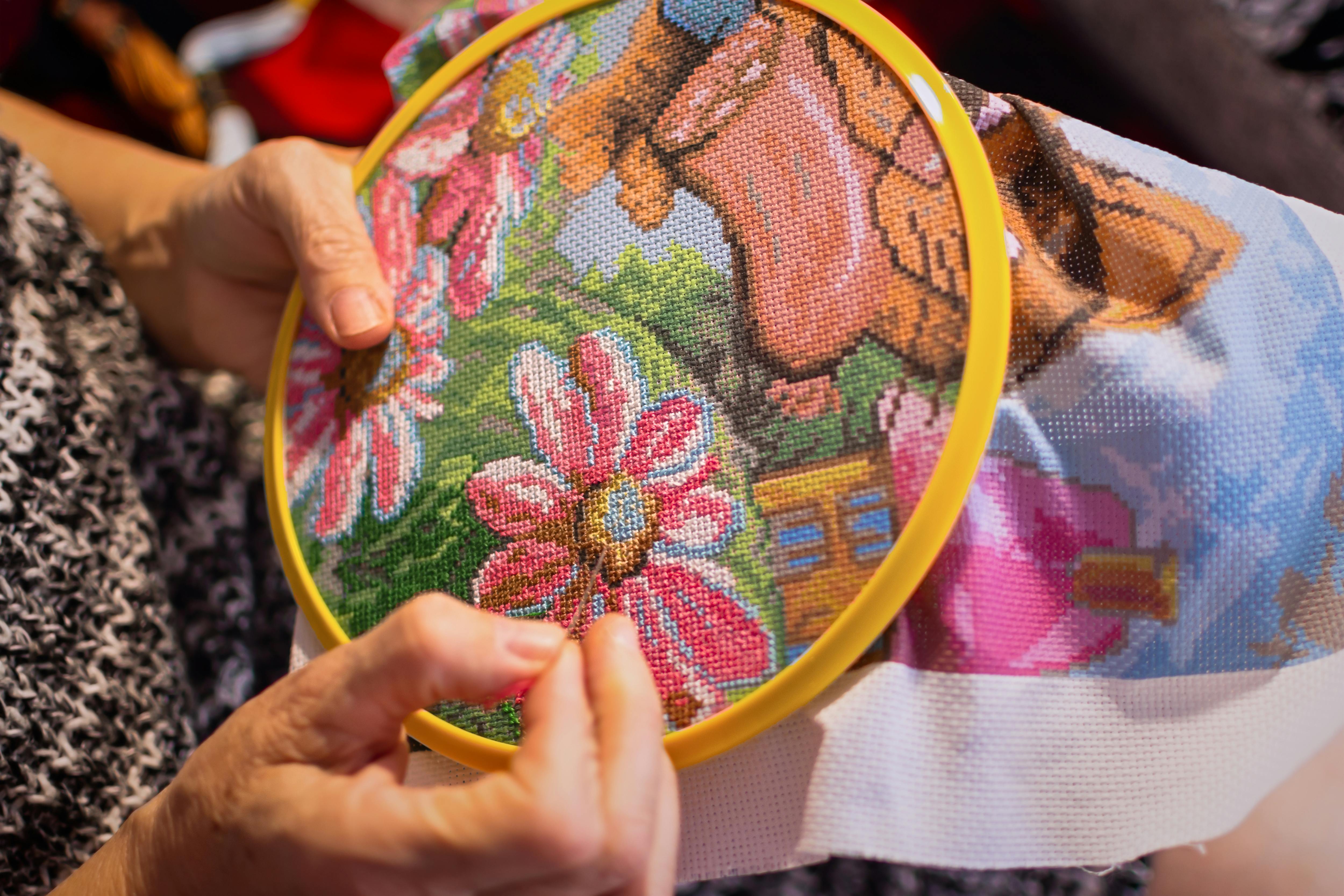  woman creating a cross stitch pattern of flowers