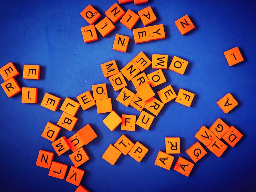 a pile of scrabble tiles in orange on purple background a pile of scrabble tiles in orange on purple background