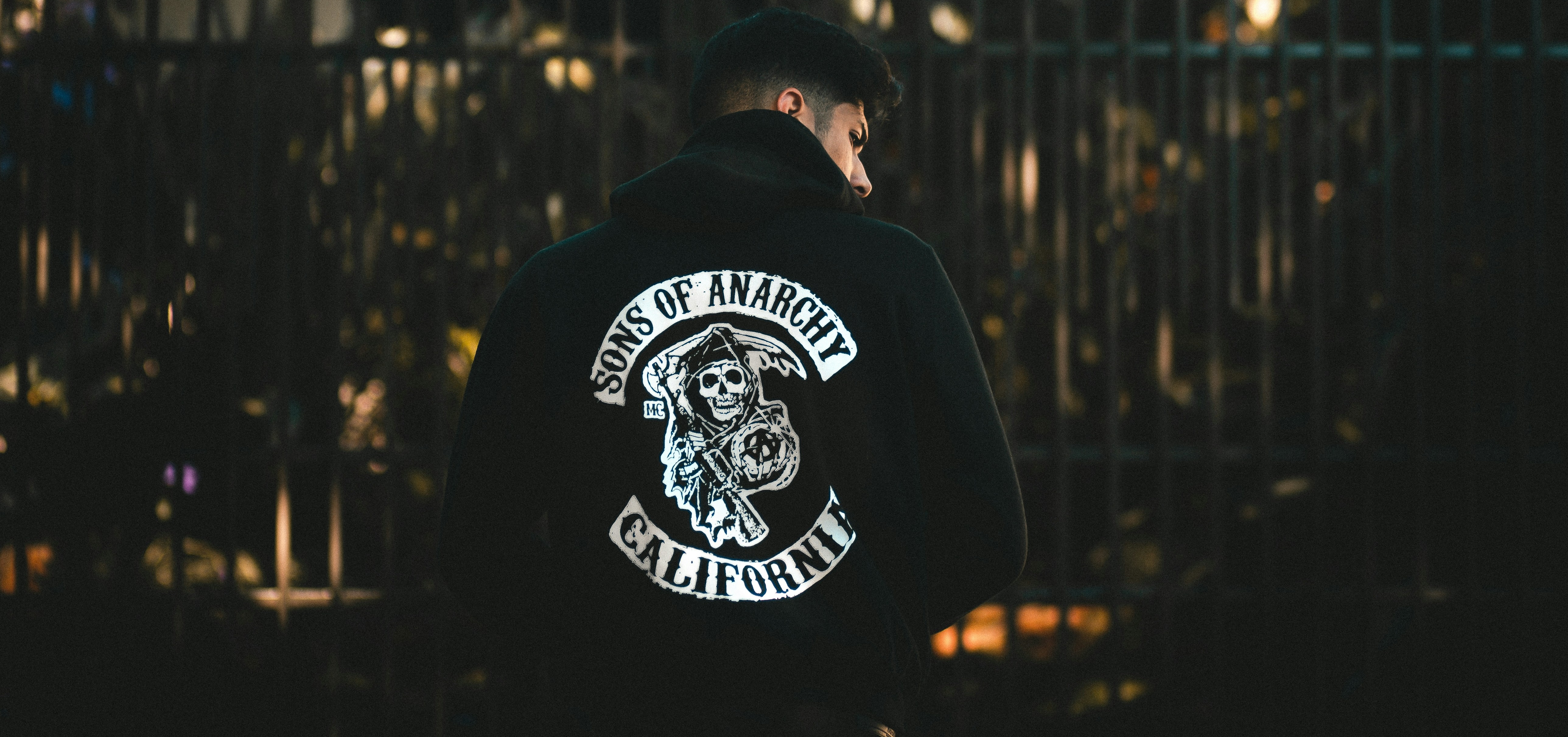 A man wearing a black hoodie with a large Sons of Anarchy patch on the back