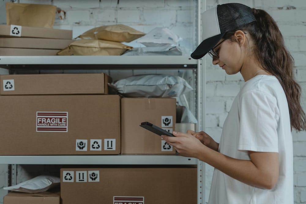 a woman standing in front of a shelve with delivery boxes  a woman standing in front of a shelve with delivery boxes
