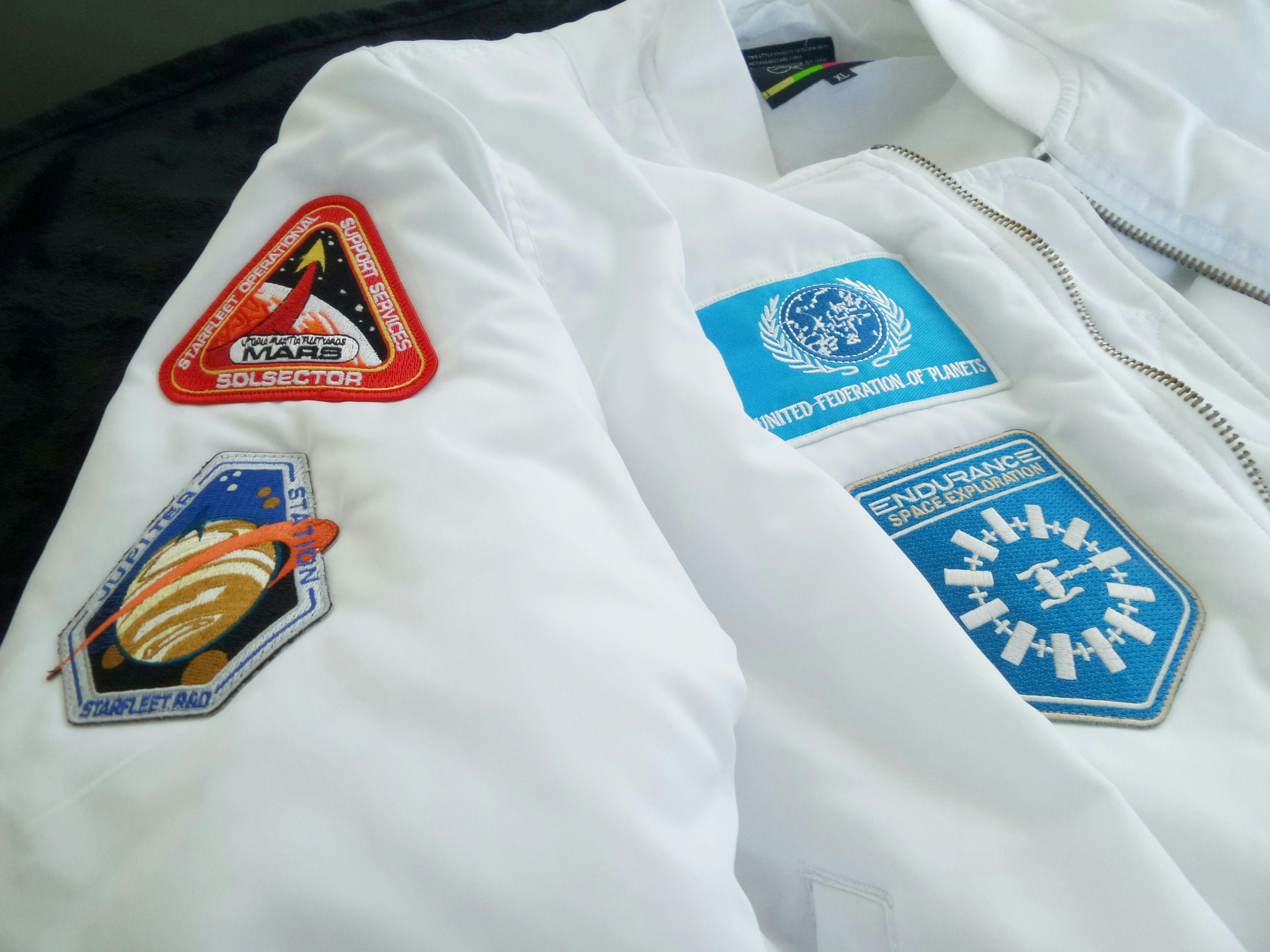  a white puffer jacket with patches attaches to the front and arm 