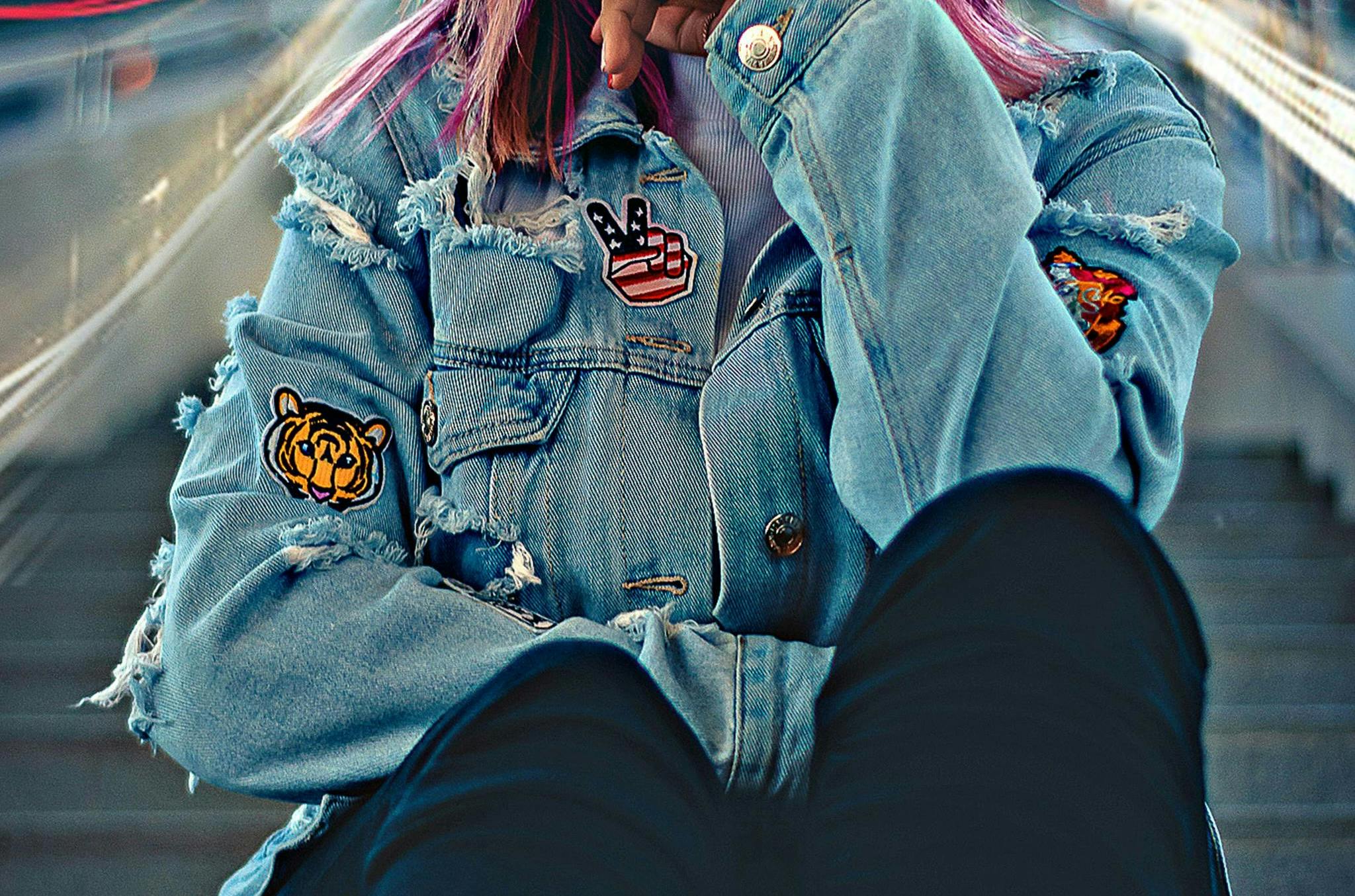  a close up of a girl wearing a jean jacket with patches on it 