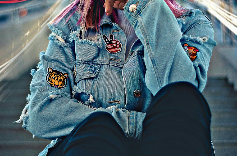 a close up of a girl wearing a jean jacket with patches on it  a close up of a girl wearing a jean jacket with patches on it