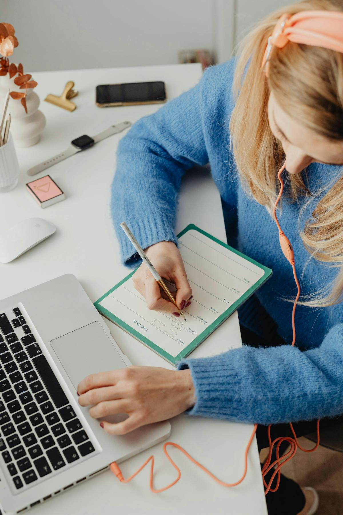 a woman working on her laptop and writing things down in her notebook   a woman working on her laptop and writing things down in her notebook