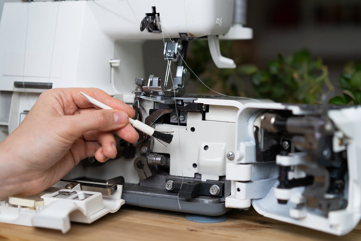 a close up of someone cleaning the underneath of a serger sewing machine a close up of someone cleaning the underneath of a serger sewing machine