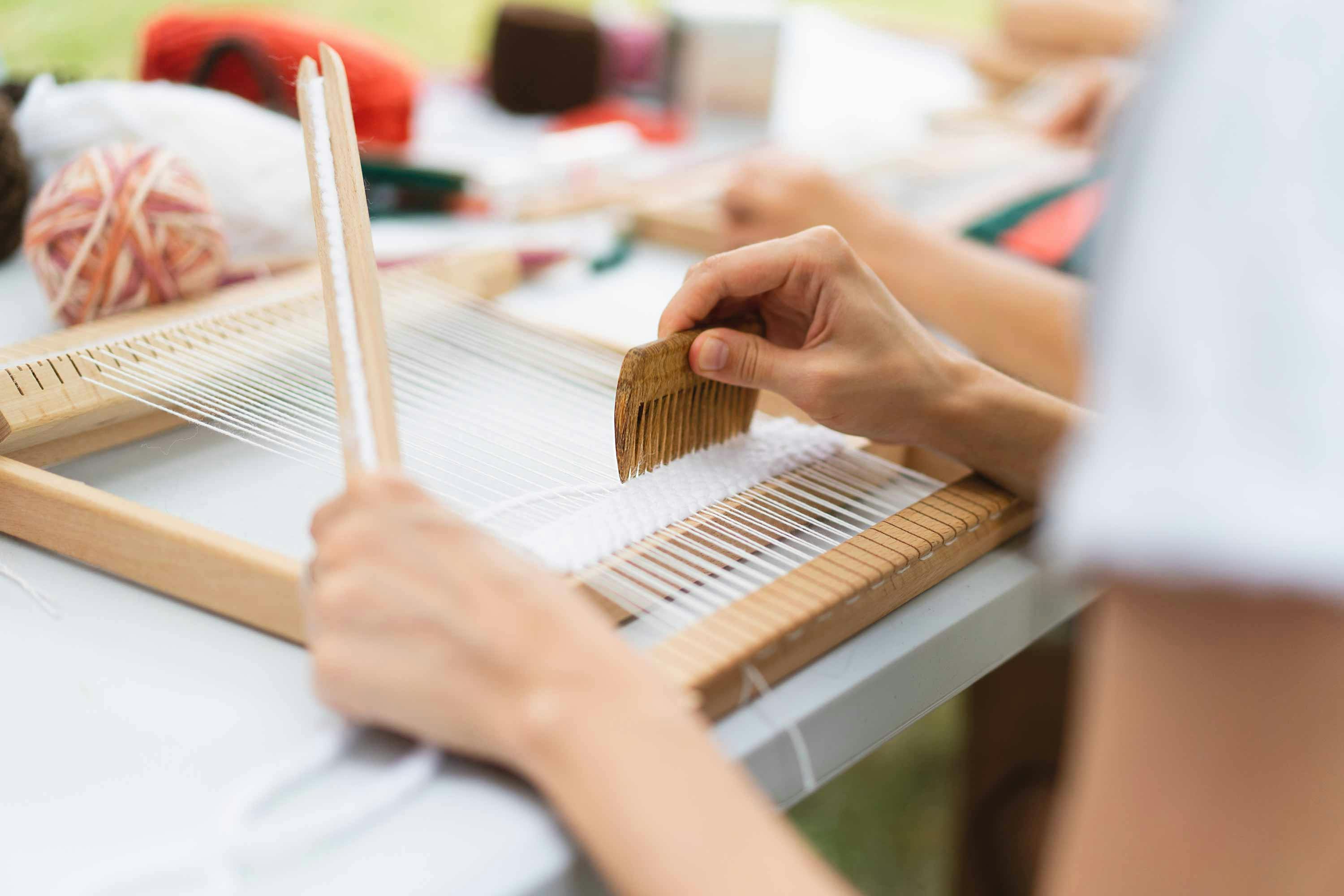  small handloom with someone weaving a piece of cloth at a desk