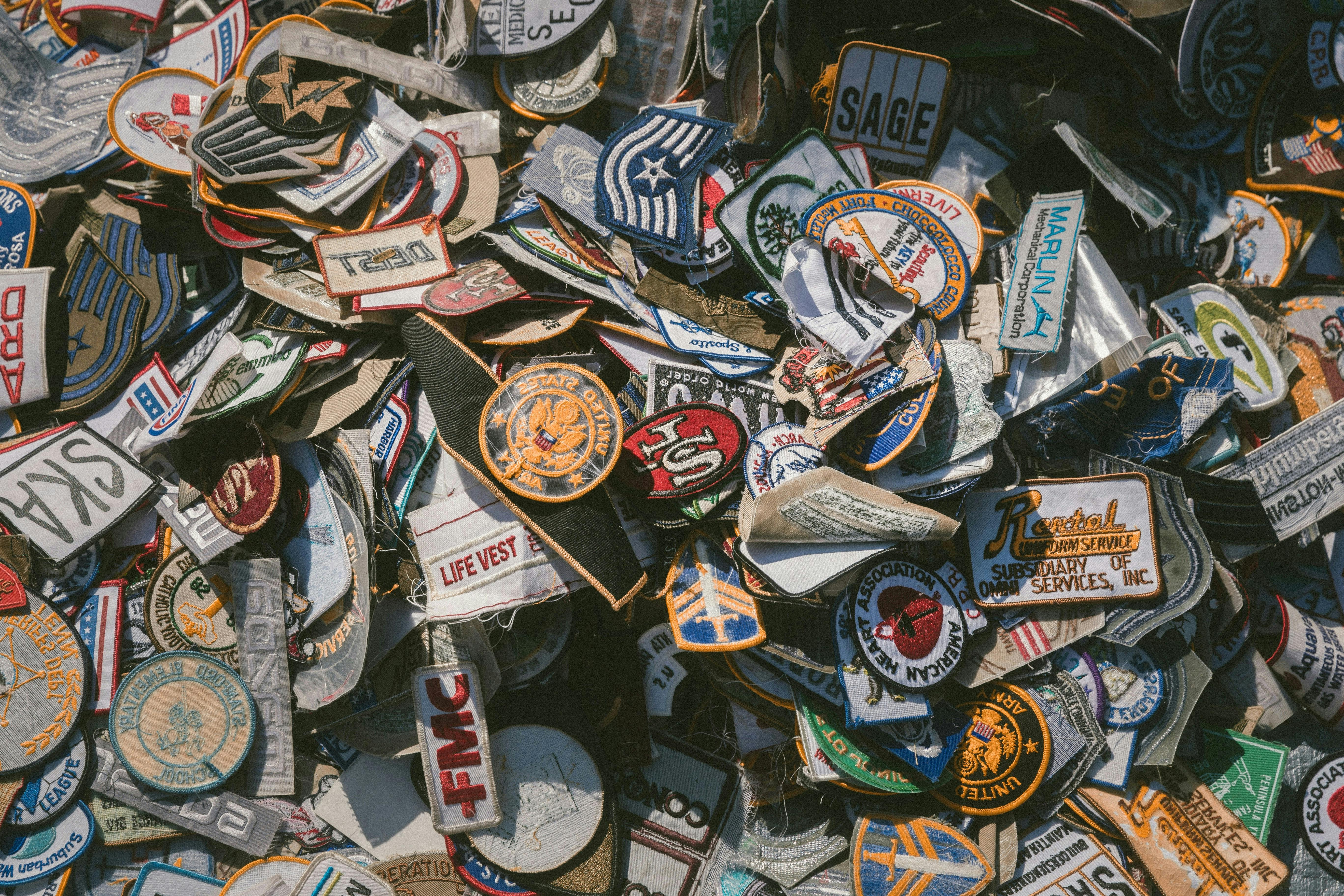  Custom embroidered patches in various shapes, colors, and designs piled together