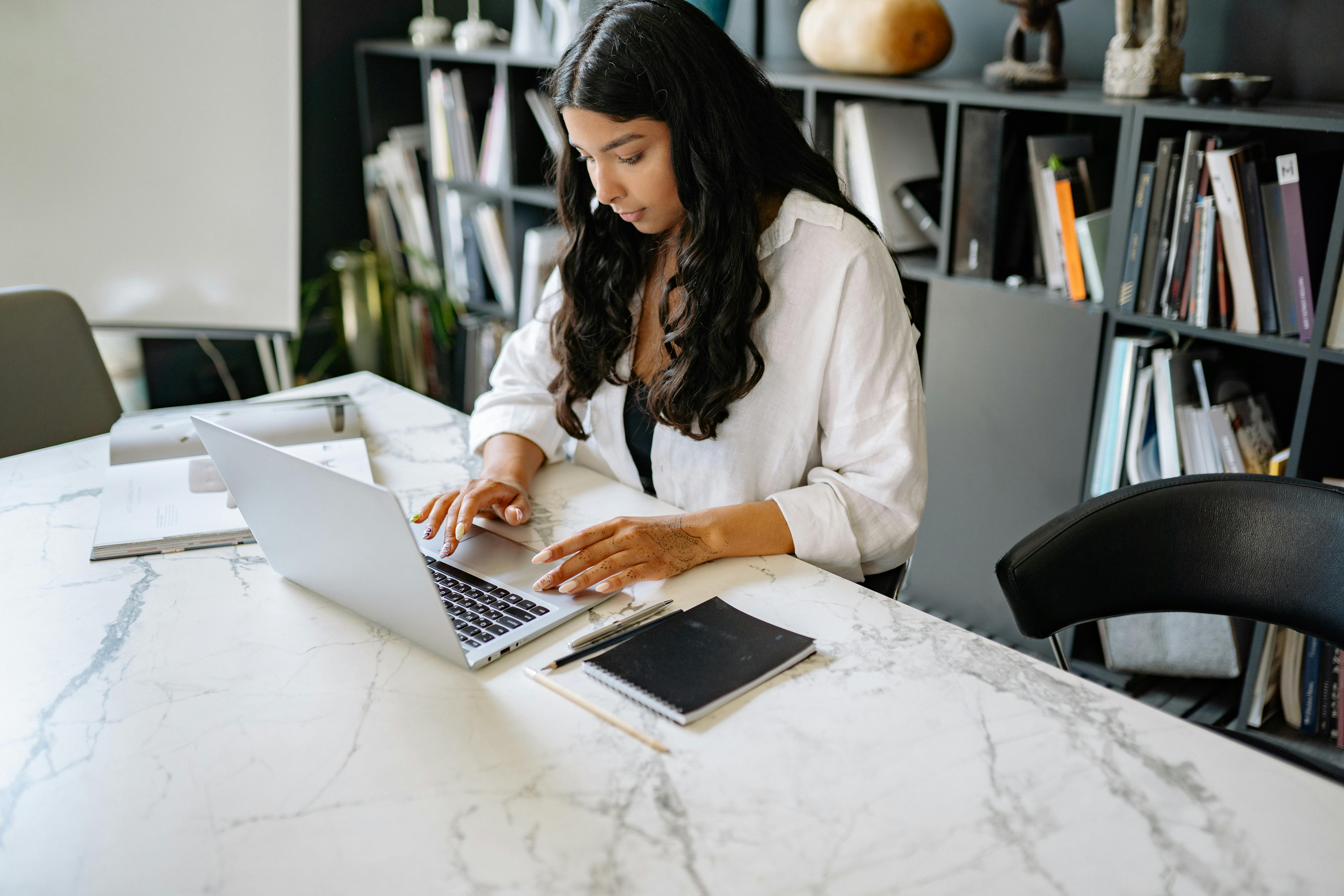 a woman sitting behind a desk and working on a laptop