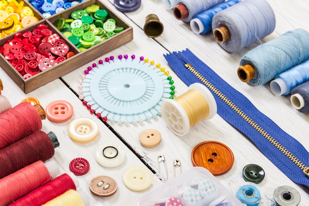 An array of colorful sewing tools like pins, scissors, buttons and threads An array of colorful sewing tools like pins, scissors, buttons and threads