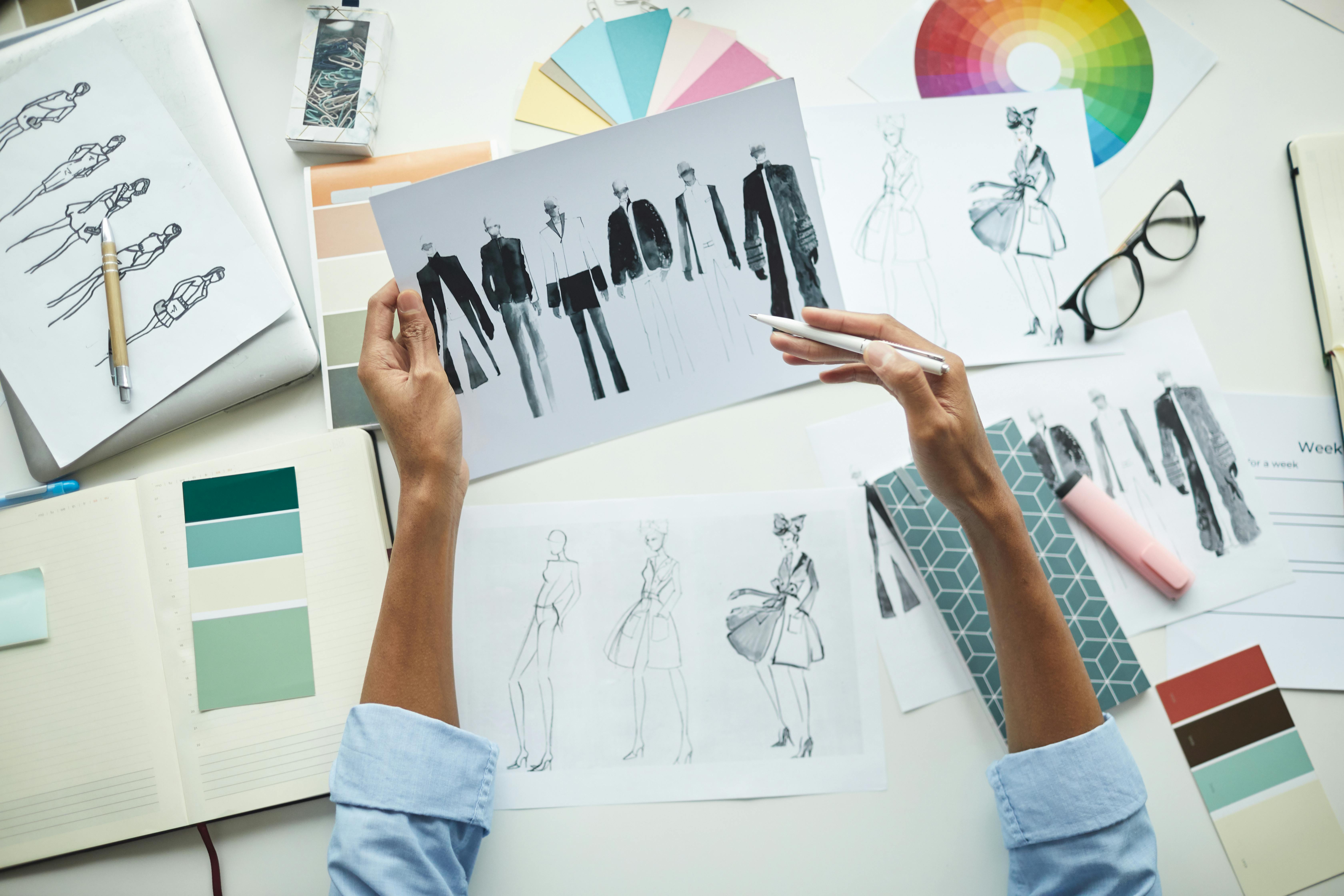 photograph of hands sketching fashion drawings