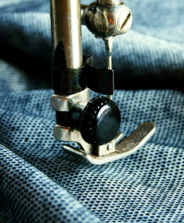  close-up van een naaimachine met blauwe gebreide stof