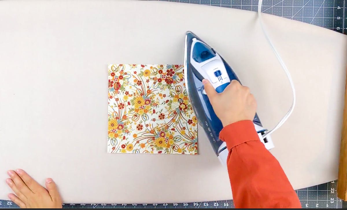  ironing a piece of fabric to make a folded fabric ornament