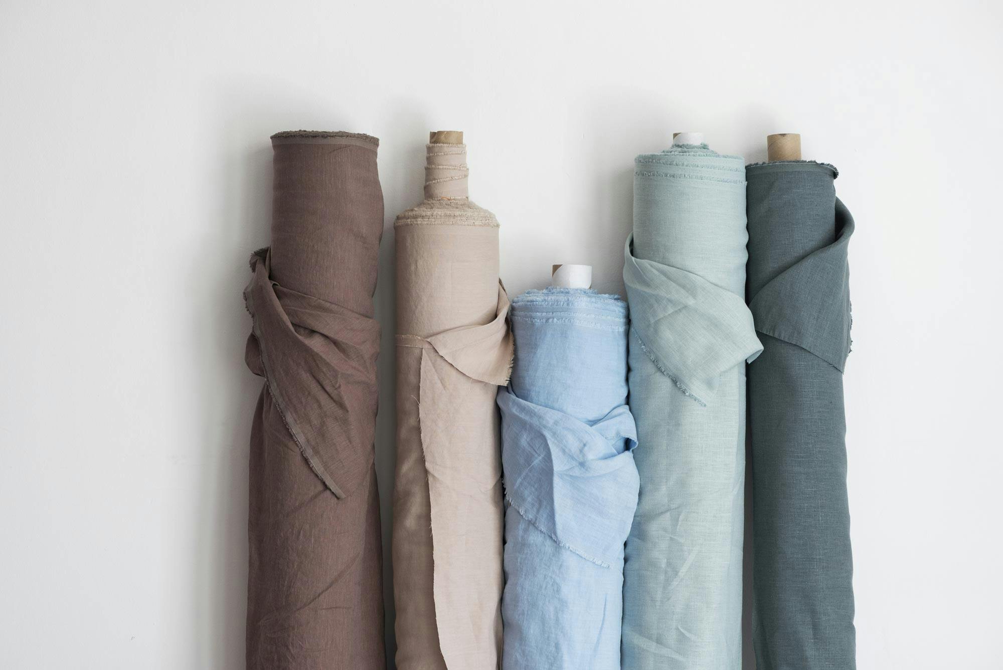 rolls of linen fabric leaning against a white wall
