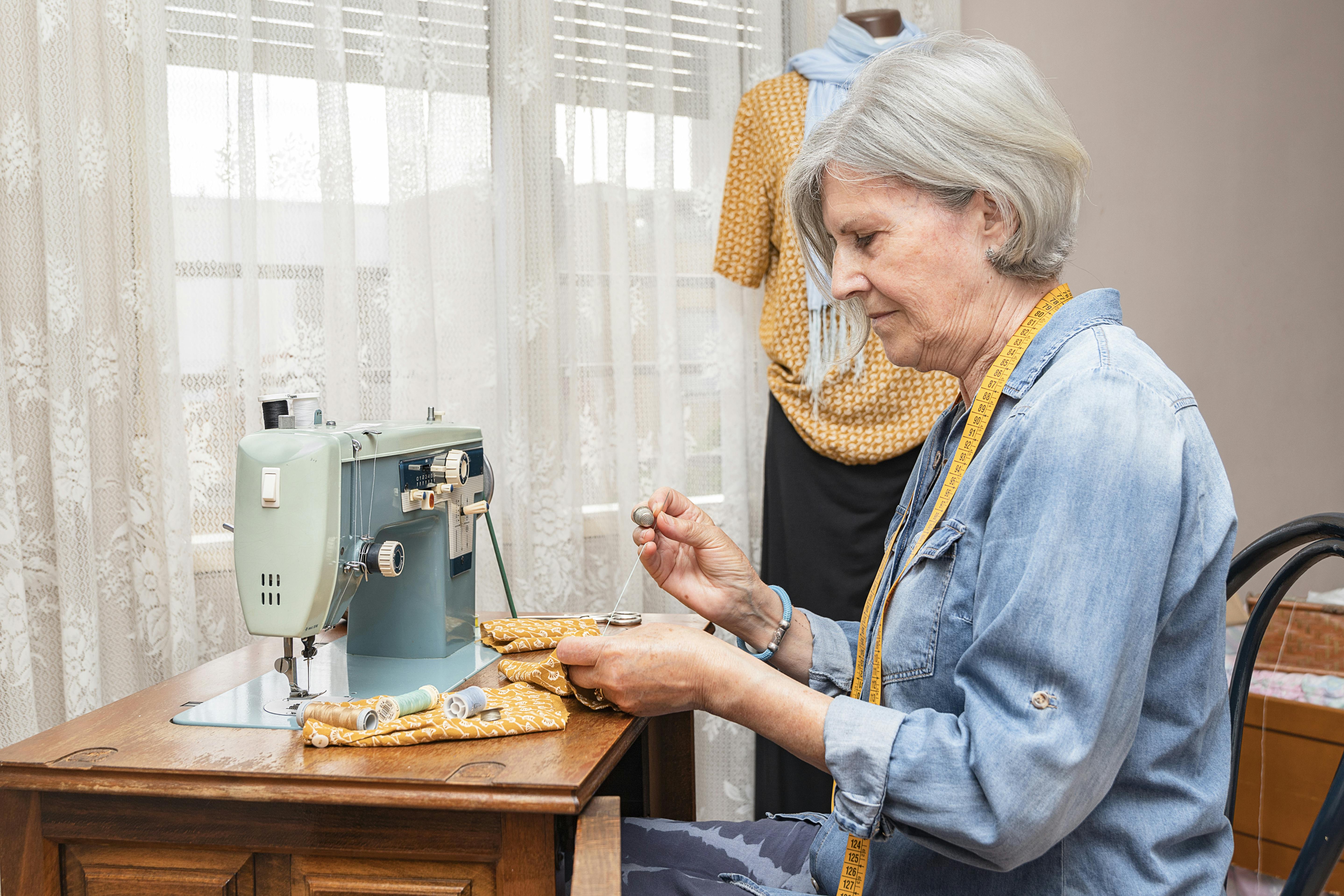  women inspecting her sewing while sitting at a sewing machine