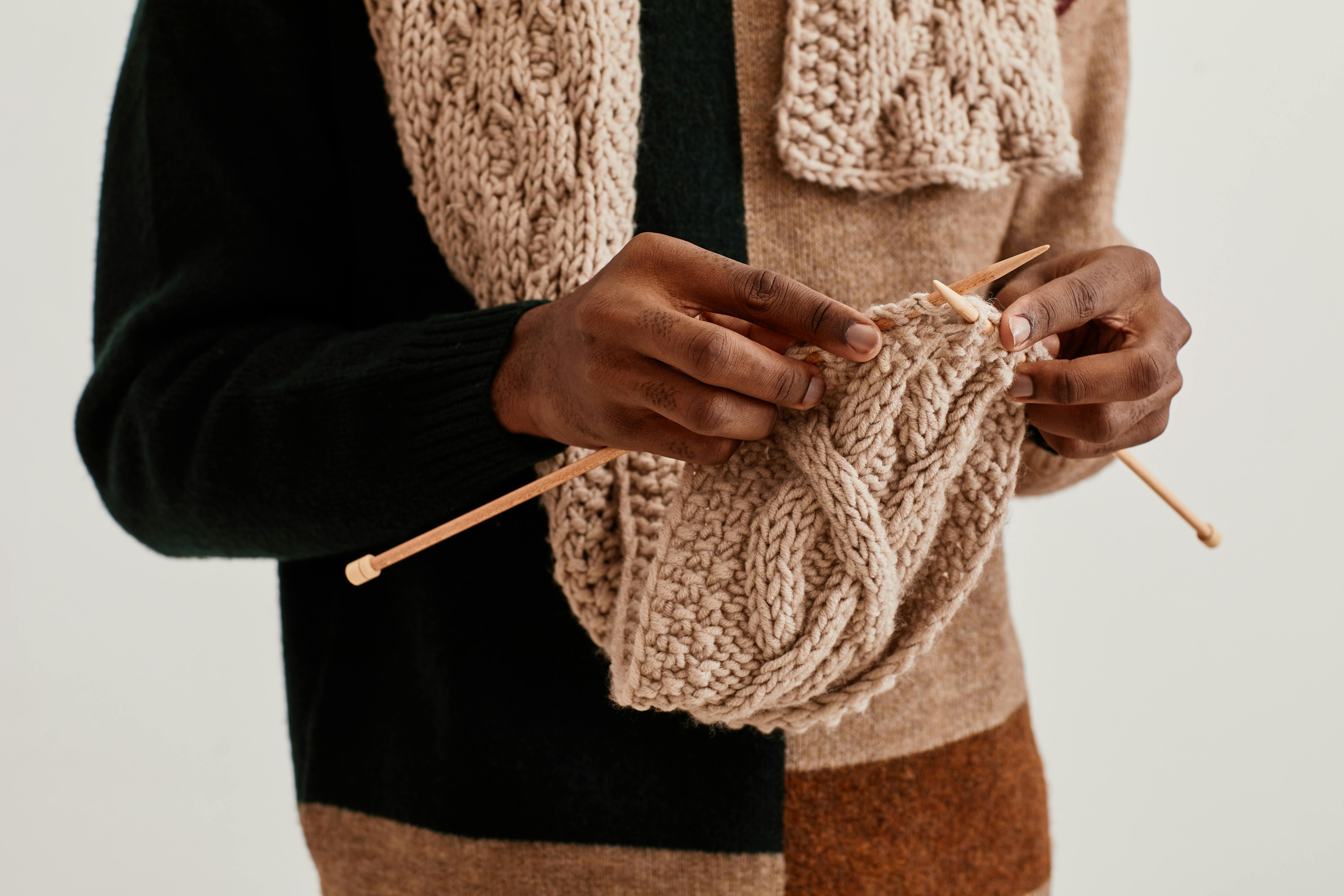  man knitting cable scarf while wearing it