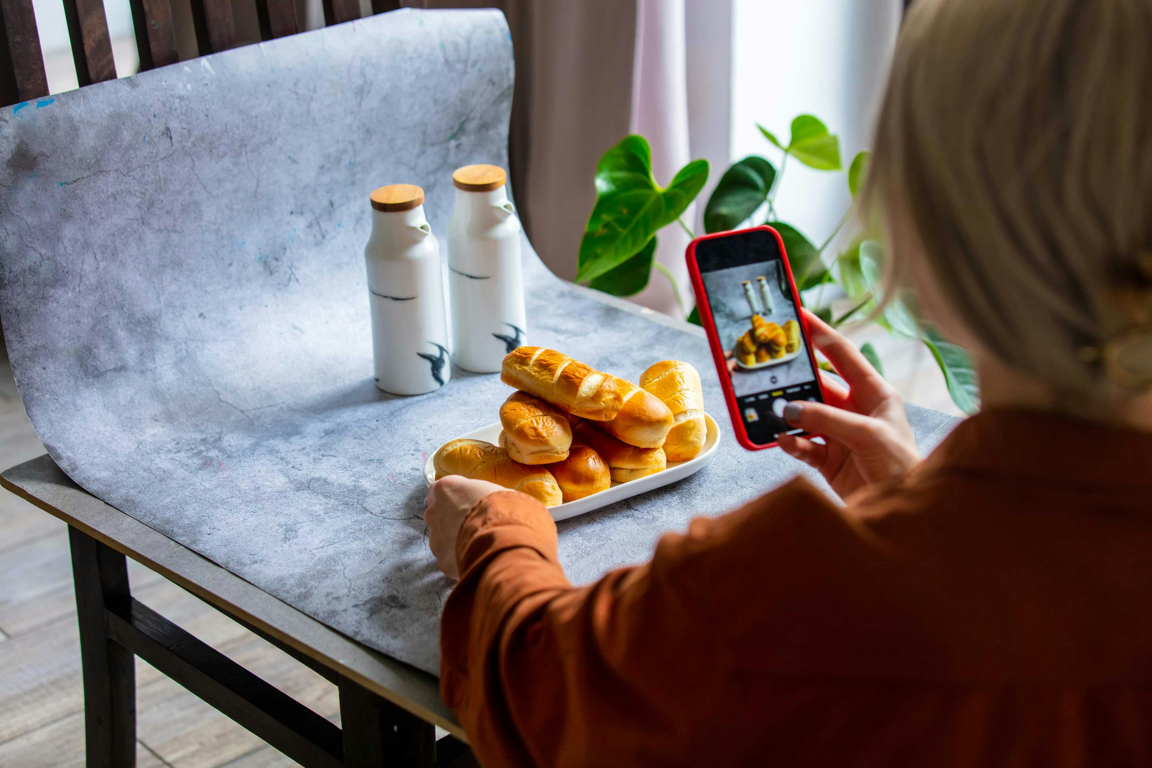  woman taking picture of products on backdrop for online store