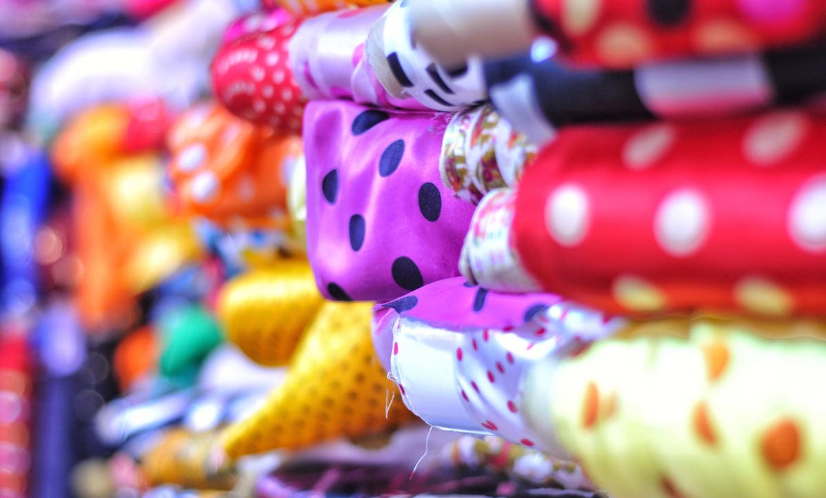  close up photograph of piles of spotted satin fabrics