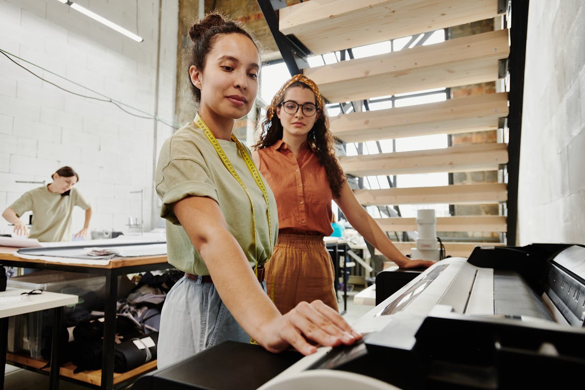 two women standing next to large industrial printer two women standing next to large industrial printer