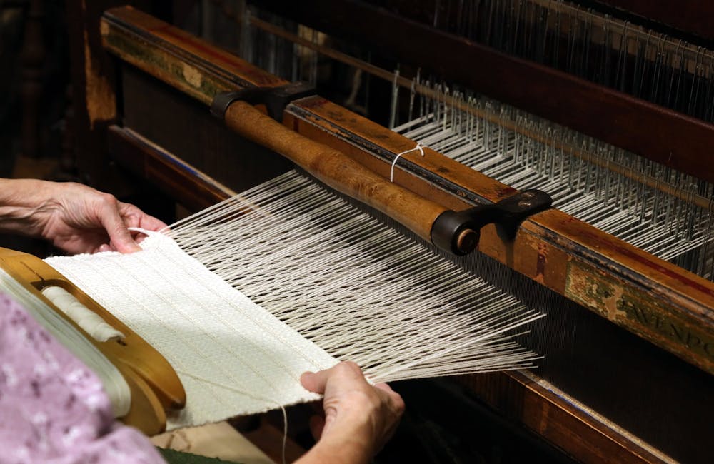  person weaving fabric on wooden loom