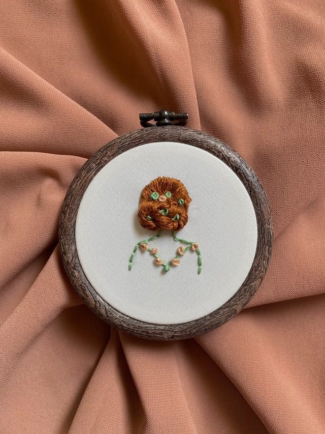  Broderie de jeune fille aux cheveux roux dans un cercle de broderie en tant que cadeau de mariage