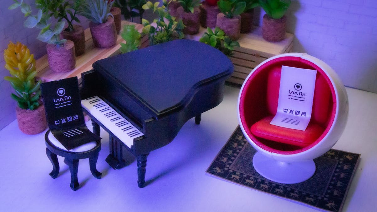  One label playing a song on a piano while another label sits in a bubble chair listening.