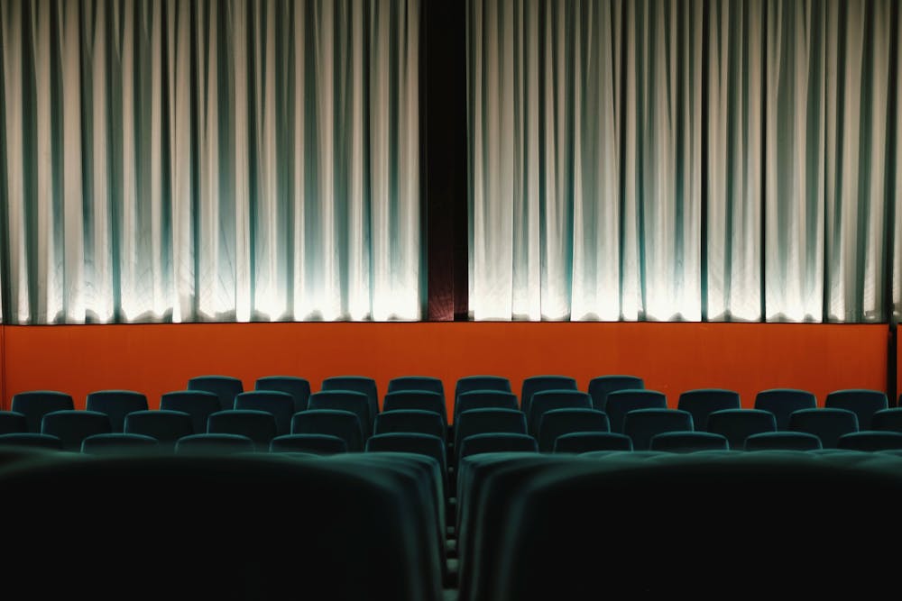  asientos de color verde de una sala de cine con cortinas de terciopelo