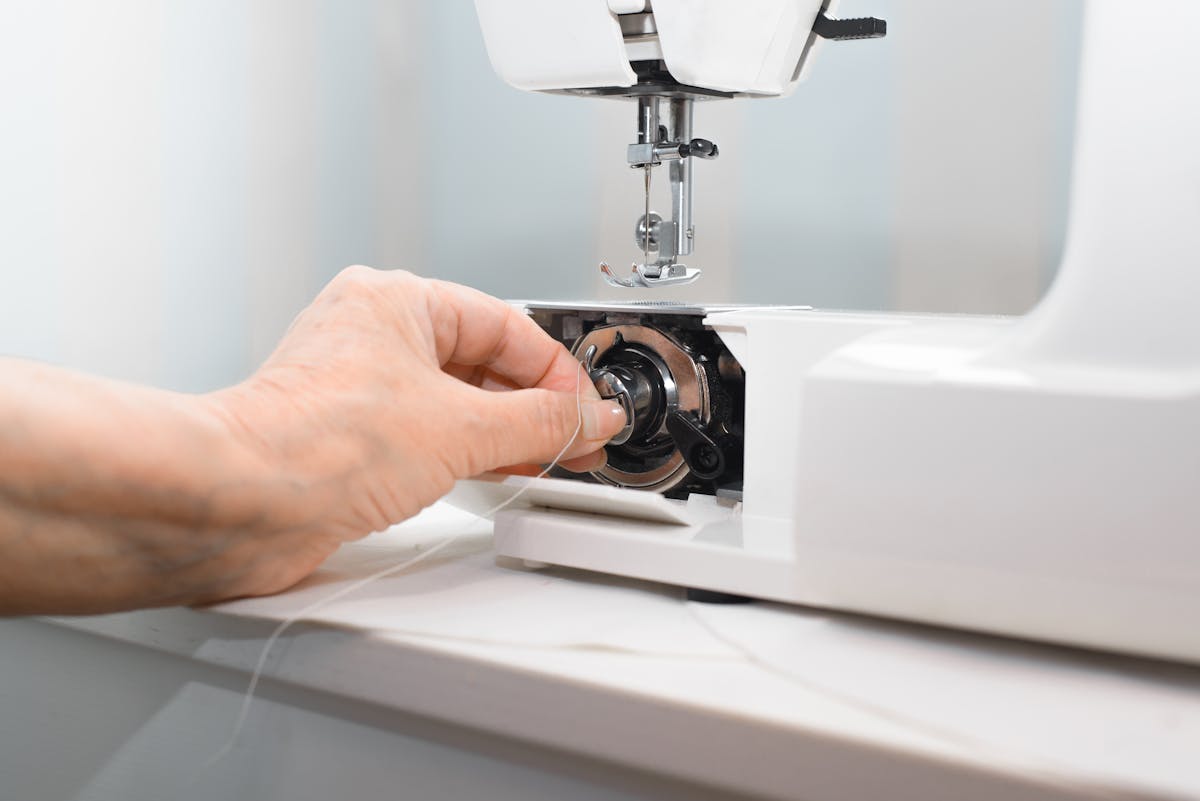  person taking the bobbin out of sewing machine