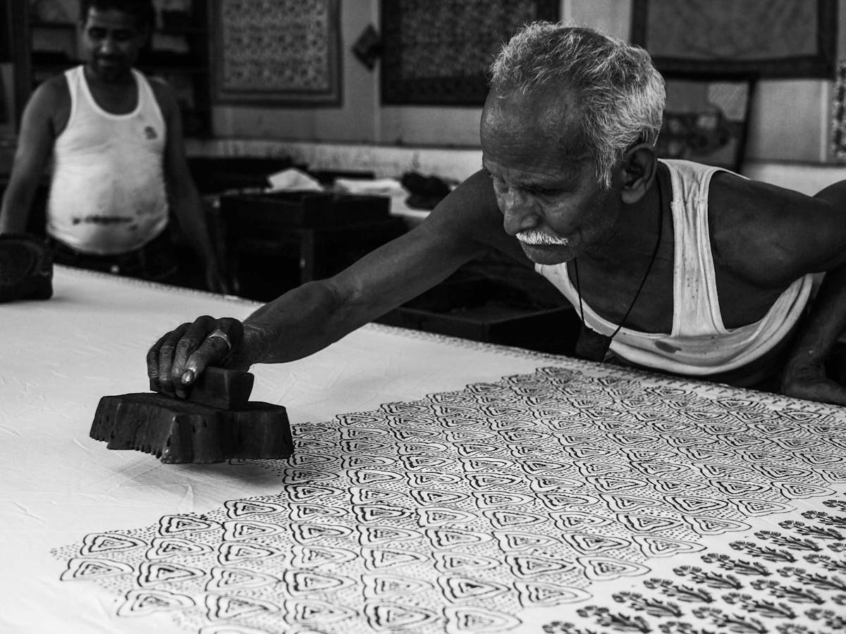  man using traditional wooden block printing to print fabric