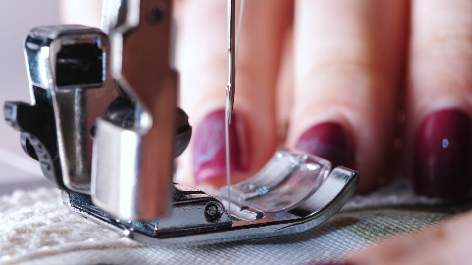  close up of sewing machine and hand