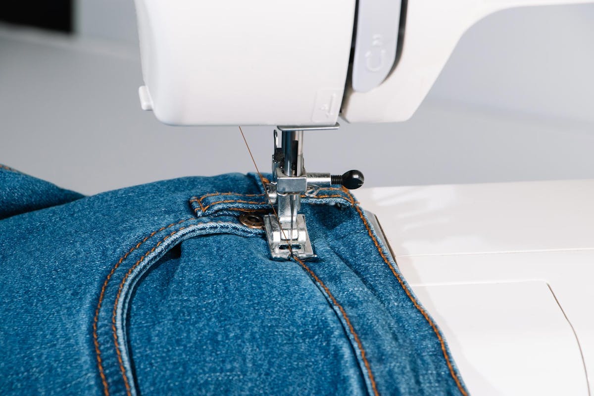  close up of denim jeans and sewing machine