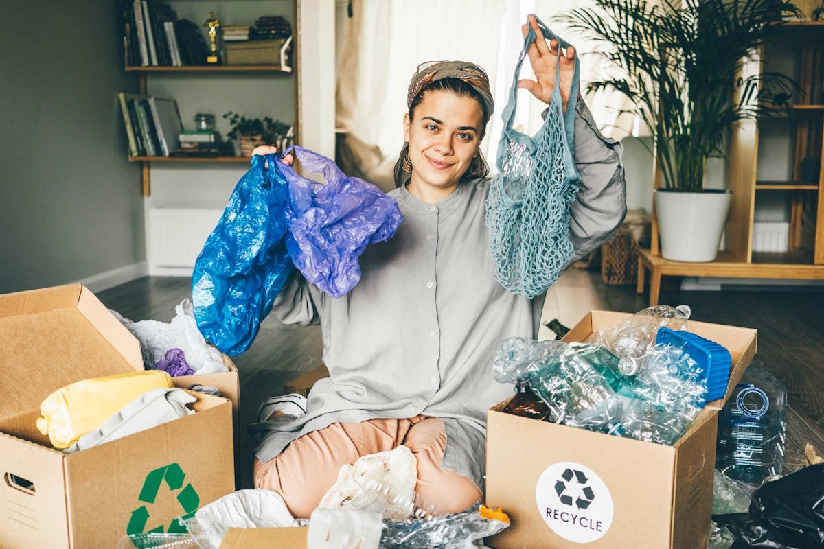  Woman sorting through recycling and plastic waste with cloth shopping bags