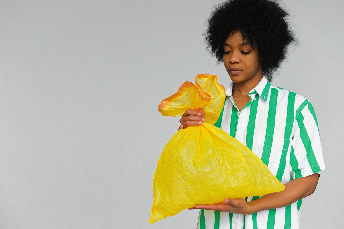  donna che ricicla con una borsa di plastica gialla