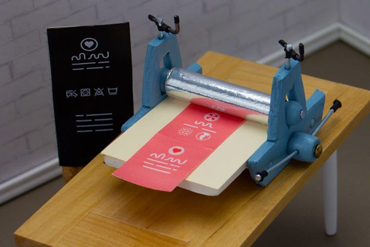 miniature printing press printing a red label.